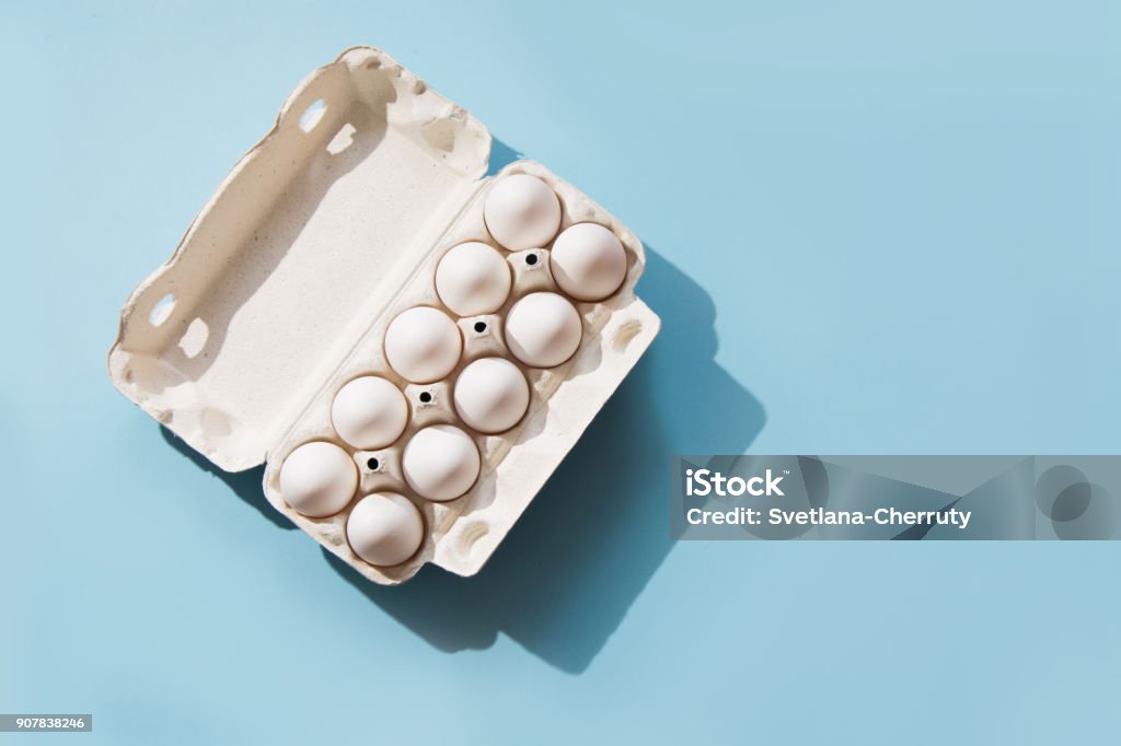 White eggs in the package on blue. Top view. White eggs in the package on blue background. Top view. Animal Egg Stock Photo