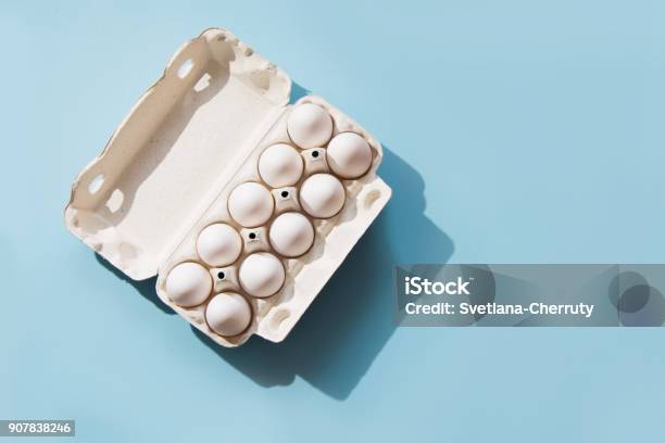 White Eggs In The Package On Blue Top View Stock Photo - Download Image Now - Animal Egg, Egg - Food, Egg Carton