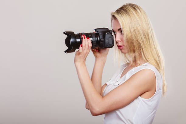 Photographer girl shooting images. Attractive blonde woman face profile taking photo with camera.