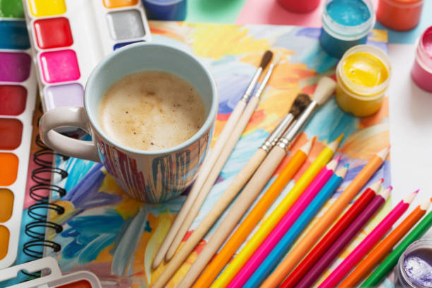 istock cup of coffee and paints, pencils on white background 907838372