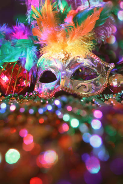 Mardi Gras, Rio carnival mask and colorful decorations. Mardi Gras or Rio Carnival mask and colorful carnival decorations.  Scene includes: gold feathered mask, colored party lights, and beads.  Objects lie on wooden table.  No people. new orleans mardi gras stock pictures, royalty-free photos & images