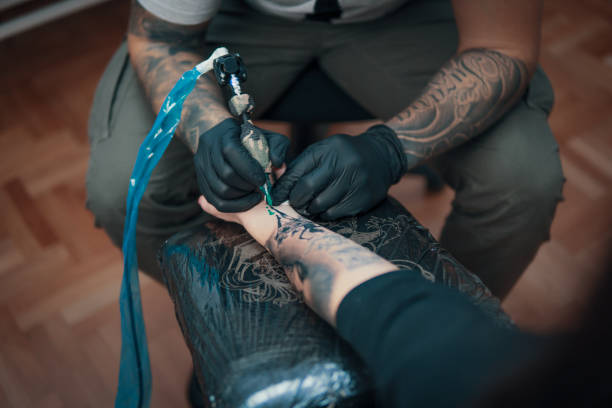 istock Tattoo master making tattoo on customer's arm 907845784