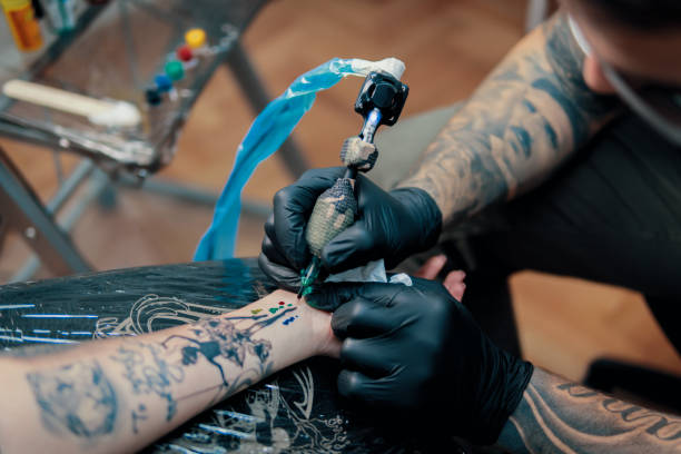 istock Tattoo master making tattoo on customer's arm 907845820