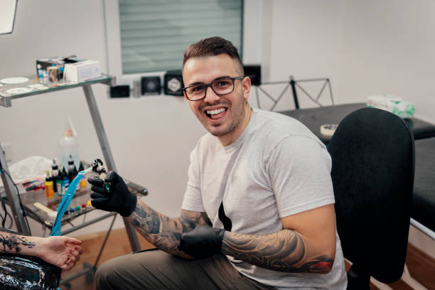 istock Tattoo master making tattoo on customer's arm 907845900