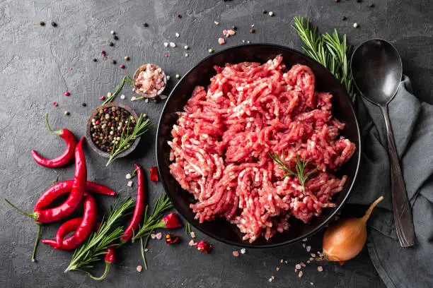 Photo of Mince. Ground meat with ingredients for cooking on black background. Top view