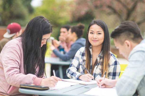 istock Multiethnic group of college students study outside at table together 907856162