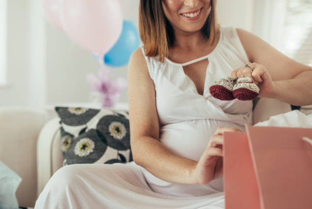 mujer embarazada sosteniendo pequeñas botitas para bebé - gift mother women baby shower fotografías e imágenes de stock