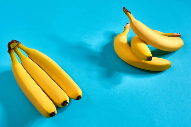 istock Fresh bananas close up on bright blue background. Flat lay. Summer concept 907858198