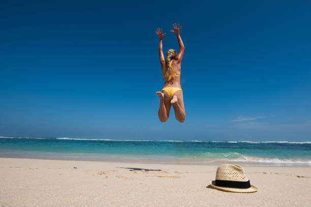 istock Good looking woman jumping on beach at sunrise. 907858208