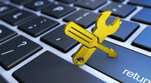 Computer service and assistance concept with a golden work tool icon on a laptop keyboard 3D illustration.
