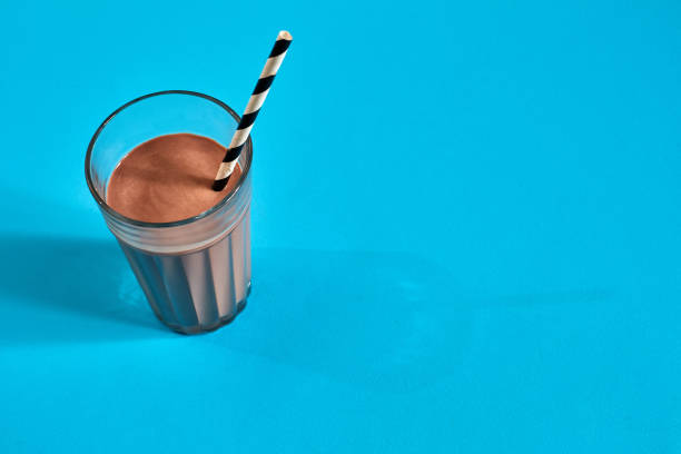 istock Glass of chocolate milk on blue background 907860166