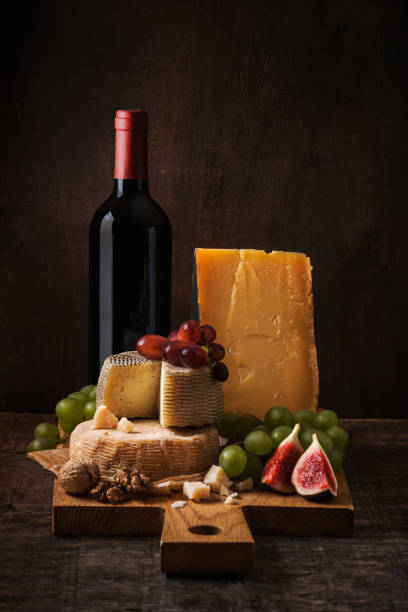 istock Dark still life with cheese board, fruits and wine 907860376