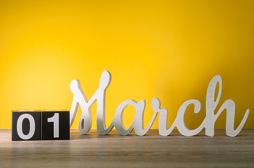1. día 1 del mes, diario calendario de madera en mesa con fondo amarillo. Tiempo de primavera, espacio vacío para el texto photo