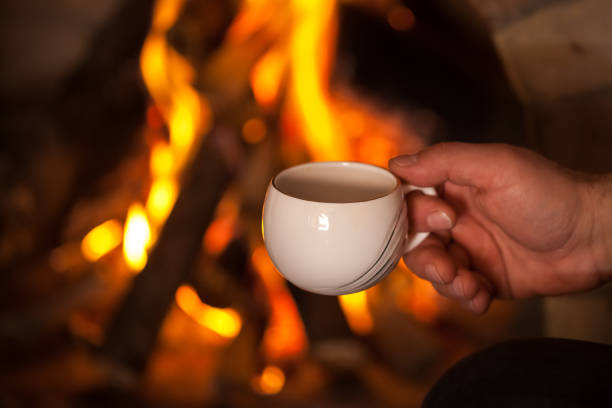 istock the man's hand with a cup by the fireplace 907860834