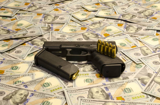 istock The weapon with blurred bullets laid down on blurred dollars. 907861094