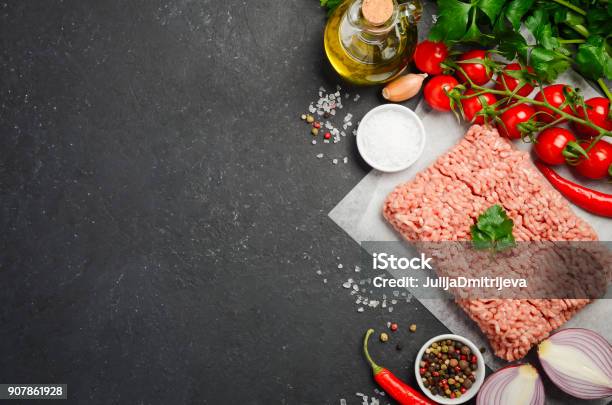 Raw Minced Meat On Paper With Fresh Vegetables And Spices On Black Background Stock Photo - Download Image Now