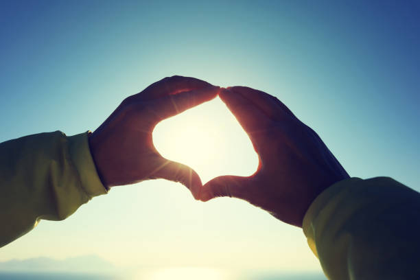 istock Hands making Heart shaped sign on sunrise seaside 907862888
