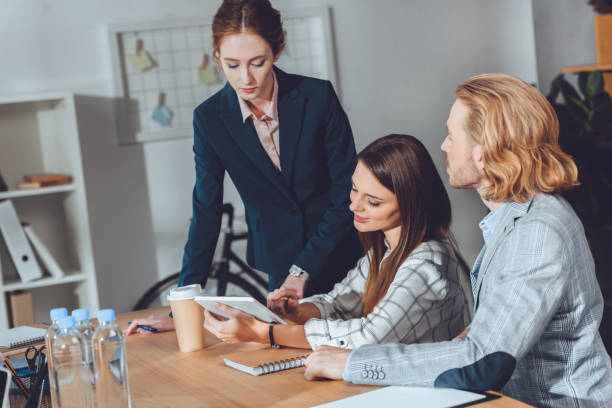 istock attractive businesspeople looking at tablet in office 907866662