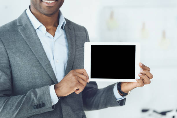 istock cropped image of smiling african american man showing tablet 907869830