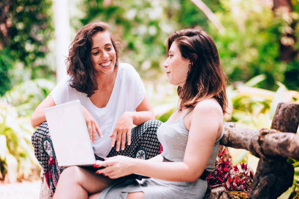 istock Two young women friends using laptop outdoors 907871580