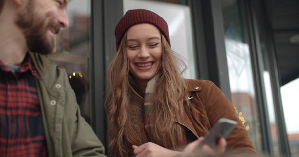 istock Young couple using cell phone while sitting in outdoor restaurant. 907873396
