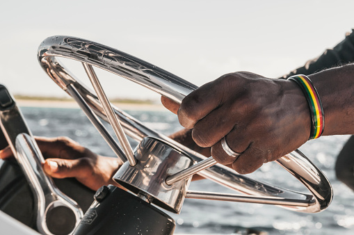 Hands hold steering wheel the boat. African man Hands of the skipper at the helm control of sailing boat.