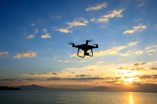 flying drone which taking photo over sunrise sea