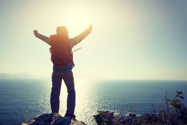 istock successful female hiker stand on sunrise seaside mountain cliff edge 907878038