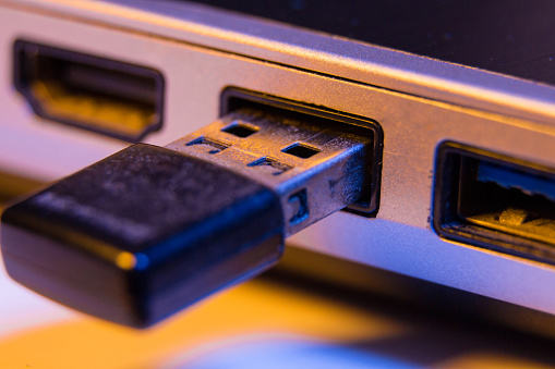 Closeup of USB flash drive inserted into port on the side of a laptop.