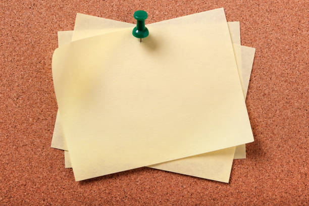 istock Several untidy yellow sticky post notes pinned to cork board 907881118