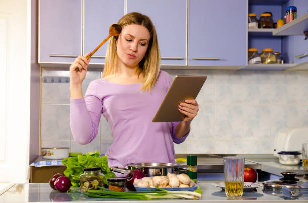 istock Woman searching cooking recipes on internet via tablet in kitchen 907881358