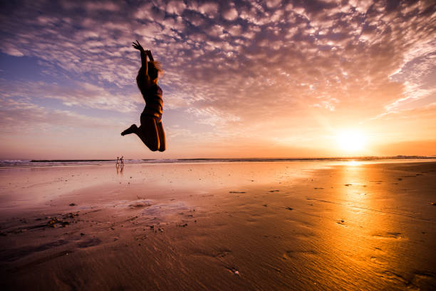 istock Young woman jumping on beach at sunset. 907882416