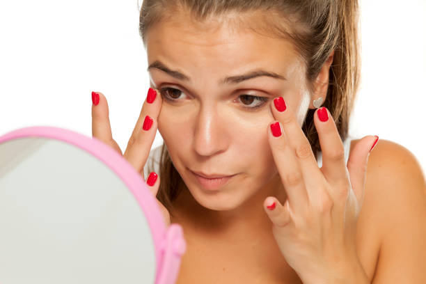 Beautiful blonde woman is refreshing her make-up while holding hand mirror.