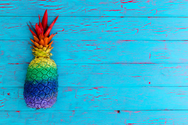istock Pineapple painted in colors on a blue table 907893898