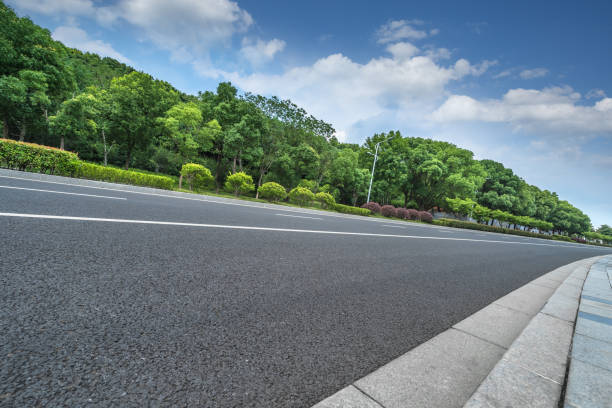 istock Asphalt road and green trees under blue sky 907895130