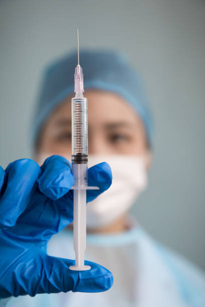 istock Doctor's hand in blue surgical glove with plastic syringe 907897310