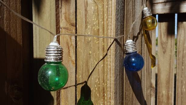 istock Multicolored string of party lights and shadow, hanging outside. 907899422