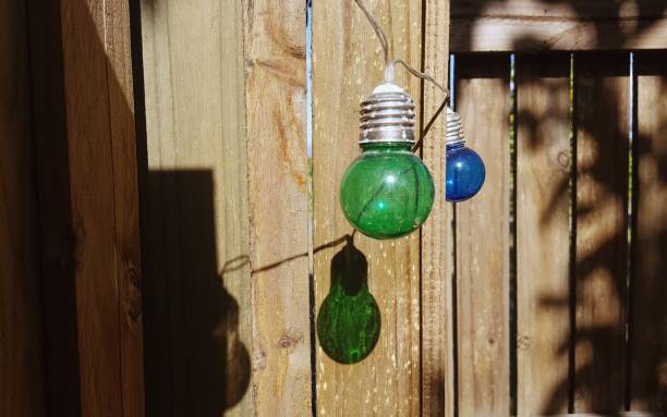 istock Multicolored string of party lights and shadow, hanging outside. 907899440