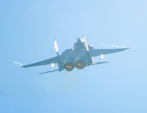 F-15 Eagle in a very close rear view, with afterburners on and condensation trails forming at the wing tip