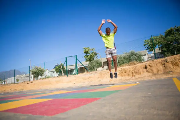 A black male does some burpees as part of his training regime outside on a court
