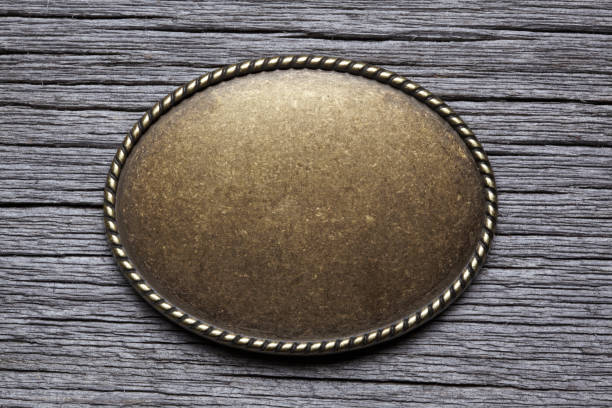Oval Silver Buckle On Weathered Wood Surface An oval shaped belt buckle resting on top of a gray weathered wood surface. buckle stock pictures, royalty-free photos & images