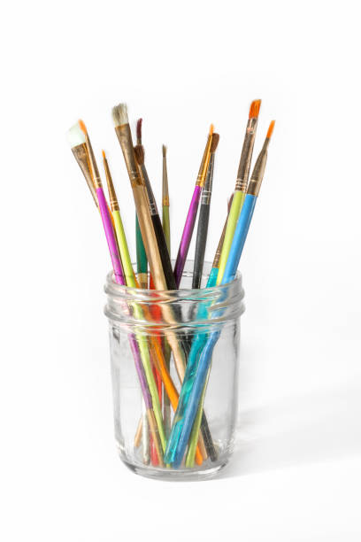 Paint brushes in a mason jar on white background