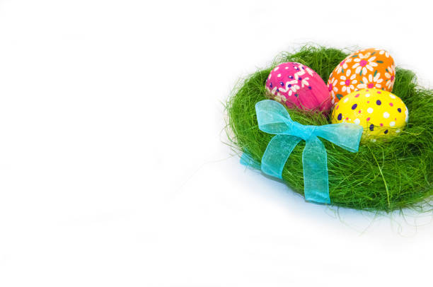 istock Easter eggs in nest from grass with a bow on white background 907919720