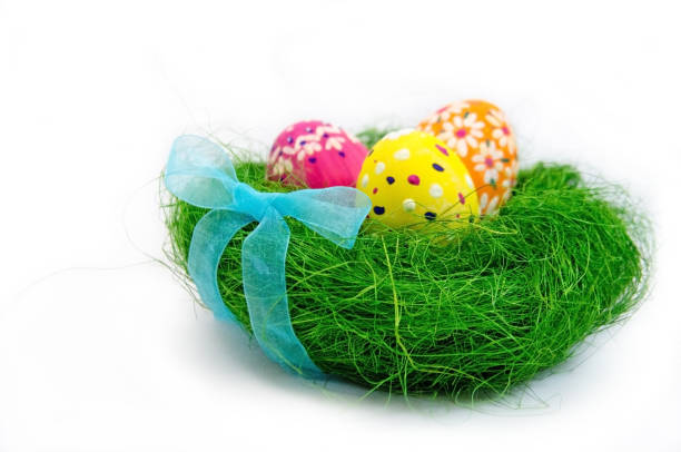 istock Easter eggs in nest from grass with a bow on white background 907919876