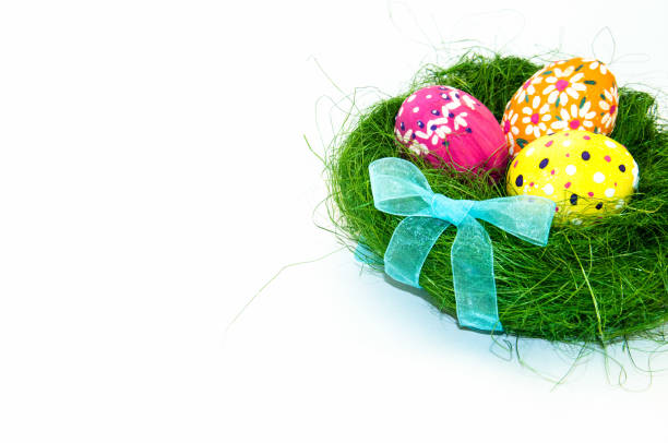 istock Easter eggs in nest from grass with a bow on white background 907919896