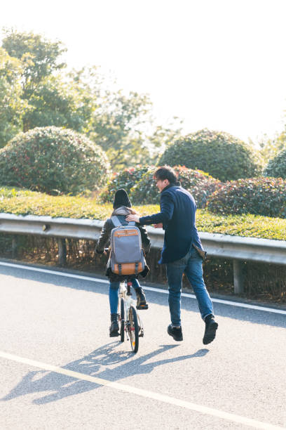 istock young man helps his girlfriend ride a bicycle 907925652