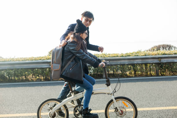 istock young man helps his girlfriend ride a bicycle 907925674