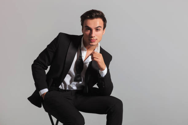istock smiling elegant man in tuxedo and undone bowtie sitting 907926806