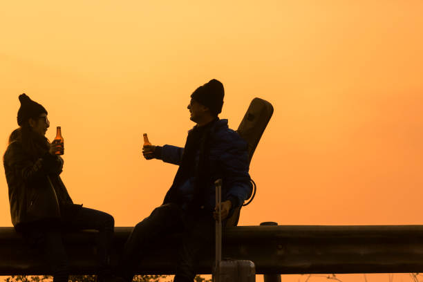 silhouette of affectionate couple toasting beer bottles at beach,China.