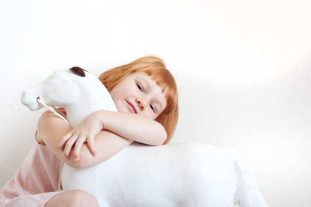 Red-haired girl hugging a toy white horse